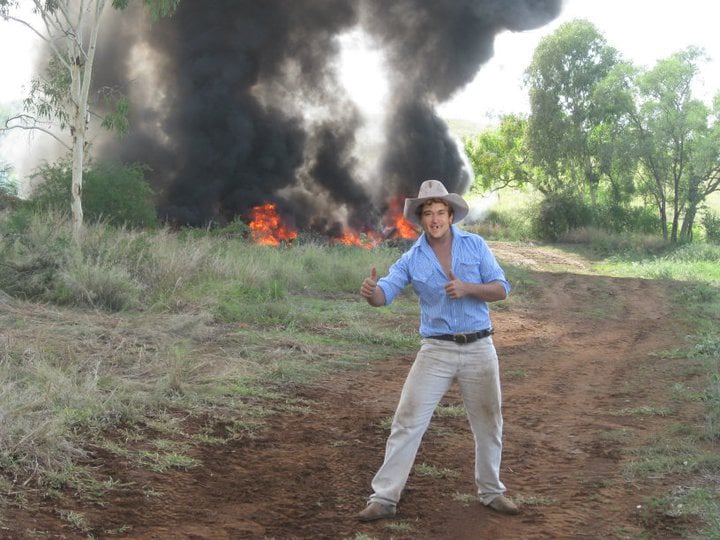 Betoota Mayor, Keith Carton, poses for a photo in front of the controlled fires that will make way for the new outback desalination plant. One of the few industries left alive after the town lost country music